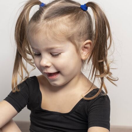 portret of a beautiful emotional 4 year old girl with two ponytails. baby sitting and smilingの写真素材