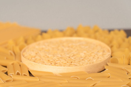 wooden round cup in the middle of italian pasta pepe rigate, snails and penne, feathers. pasta...