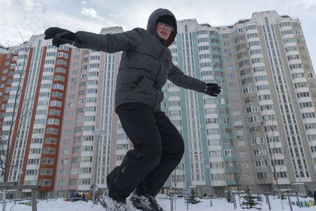 boy jumping from the mountain in the snow against the background of multi-storey buildings. winter holiday conceptの写真素材
