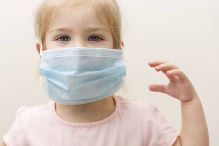 little girl in a disposable mask on a light background. Chinese virus epidemic protectionの写真素材