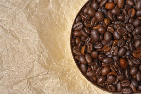 coffee grains in a round wooden jar on a background of crumpled parchmentの写真素材