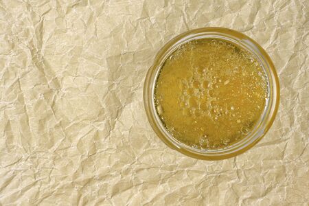 round jar with orange marmalade on a background of crumpled parchmentの写真素材