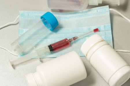 tablets in jars, antiseptic gel, disposable mask, syringe with a red vaccine. development of a...