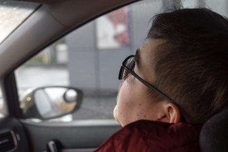 a teenager with glasses sleeps in the passenger seat of a car