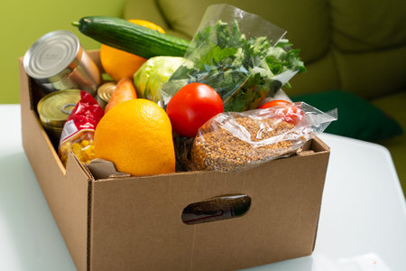 products in a cardboard box are on the kitchen table. food delivery