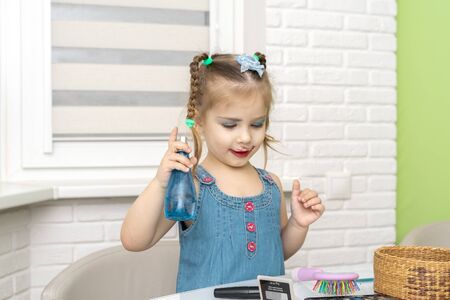 little girl a preschooler in a blue dress does makeup mom's makeupの写真素材