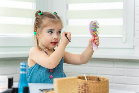 little girl a preschooler in a blue dress does makeup mom's makeupの写真素材