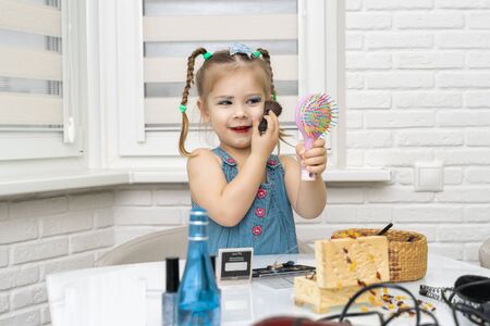 little girl a preschooler in a blue dress does makeup mom's makeupの写真素材