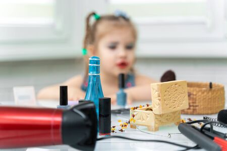 girl 4 years old makes makeup mom's makeup. focus on cosmetics, girl in blurの写真素材