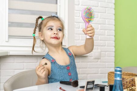 3-4 years old girl in a dressing dress is painted with mother s makeupの写真素材