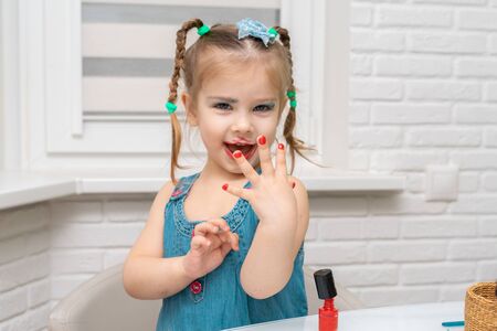 little girl brightly colored makes a manicureの写真素材