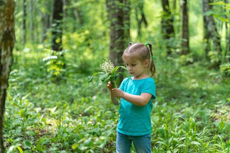 little girl in the forest with a bouquet of lilies of the valleyの写真素材