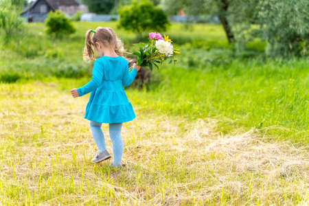 little girl in a red dress eating a big piece of red watermelon and smilingの写真素材