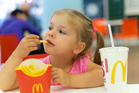 07 19 2020 Russia, Moscow.little girl eating french fries at mcdonald'sのeditorial素材