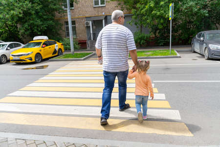 07 19 2020 Russia, Moscow. father and little daughter cross the road at a pedestrian crossingのeditorial素材