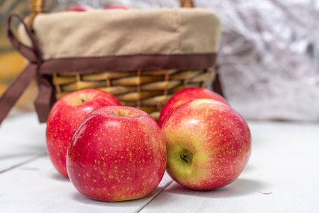 red juicy fresh apples on wooden background and basket