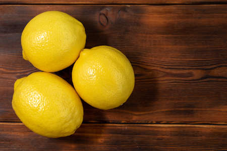 three whole yellow lemons on a wooden table, close-upの写真素材