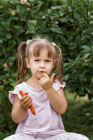 beautiful little girl eating carrots in the country.healthy food conceptの写真素材