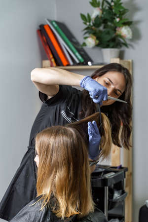hairdresser doing hair to a young girl in a beauty salonの写真素材