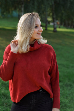 young blonde woman posing outdoor in red polover