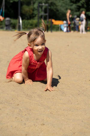 a little girl crawls on the sand and laughs. summer vacation conceptの写真素材