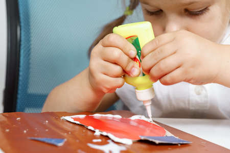 children's creativity. child glues colored paper. little girl is doing paper art with a teacher.の写真素材