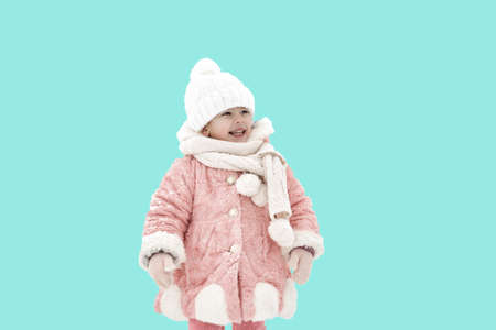 beautiful little girl in a pink fur coat, hat and scarf, isolate on a blue background. child in warm winter clothesの写真素材
