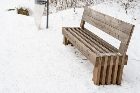 wooden bench in winter park. public park covered with snow