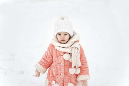Happy baby girl rejoices in falling snowの写真素材