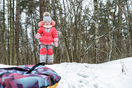 baby Girl having fun on snow tube.Child is riding a tubing. Winter holidays, holiday for children in...