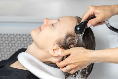 young woman enjoys shampooing in beauty salonの写真素材