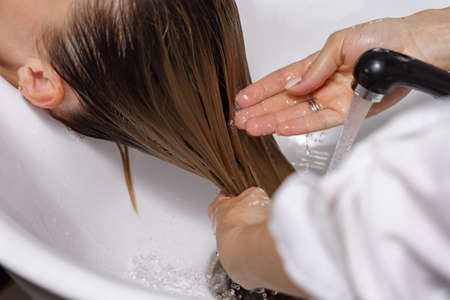 Shampooing hair in spa beauty salon of young woman, hairdresser caring for client.の写真素材