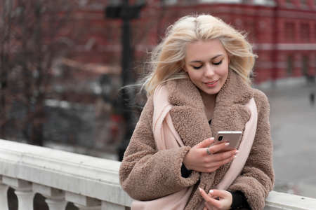 01 14 2020 Moscow, Russian Federation. young woman looks into her smartphone in the center of moscowのeditorial素材