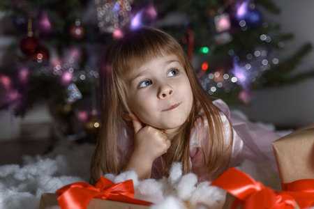 cute little girl thinking by the christmas tree