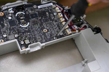 Electronic circuit board and wiring inside a modern robot vacuum cleaner. foreman repairs the device with a screwdriverの写真素材