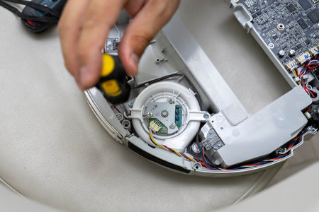 robot vacuum cleaner repair. A man is fixing robot vacuum cleaner during open the cover showing an electronics circuit board in side the machine.の写真素材