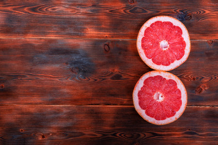 two halves of ripe red grefruit on a wooden background. space for textの写真素材