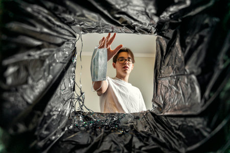 a man throws a disposable mask into the trash. view from the trash canの写真素材