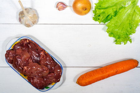 chicken liver and vegetables on a wooden background. set of raw foods for cooking. space for text and copy spaceの写真素材