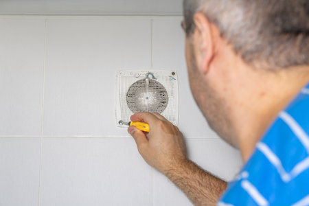 master cleans a very dirty exhaust fan in the bathroomの写真素材