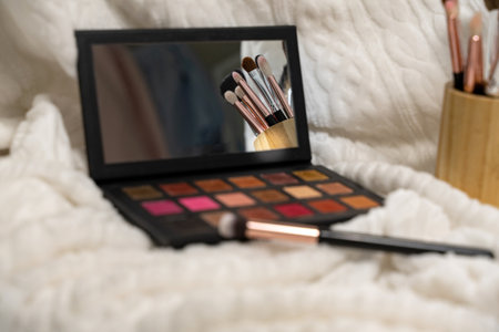 a collection of professional makeup brushes and an eyeshadow palette. brushes are reflected in the mirror. focus on the mirror.の写真素材