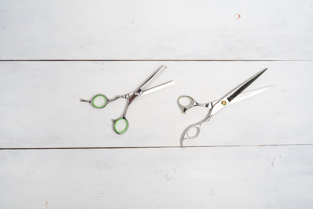 scissors on the desktop of a beauty salon on a white wooden background, top view space for textの写真素材
