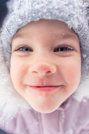 portrait of a beautiful little girl 4 years old in winter clothes outdoor. wide angleの写真素材