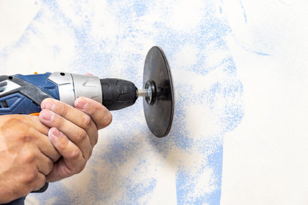 The plasterer levels the surface of the wall with a sander. the master removes the old paint from the surface. Copy space.の写真素材