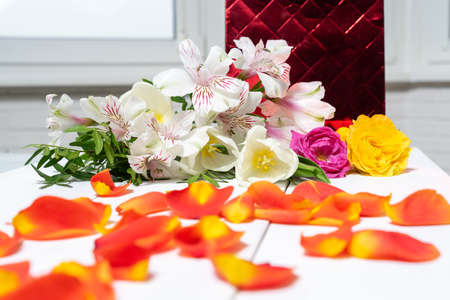 composition of a gift package, rose petals and a bouquet of flowers. holiday and congratulations conceptの写真素材