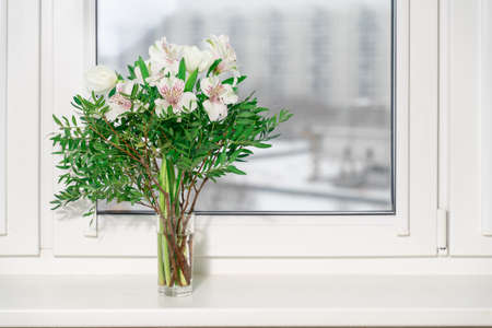 bouquet of decorative white lilies in a vase on the window.の写真素材