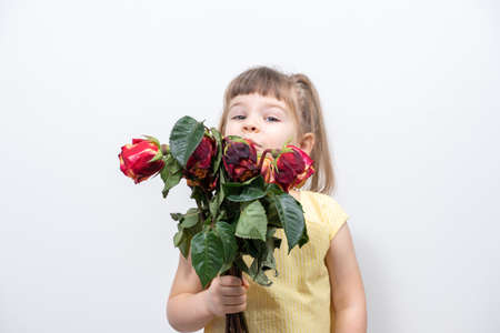 sad child girl holding a bouquet of dried flowersの写真素材