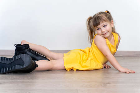 child girl lying on the floor in daddy's shoesの写真素材