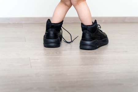 childs feet in large mens sneakers close-up on the laminate floor. sports and fitnessの写真素材