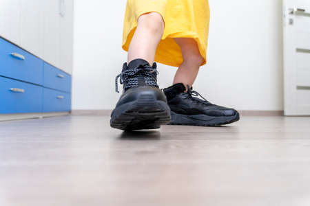 Little girl trying on her daddy's big bootsの写真素材